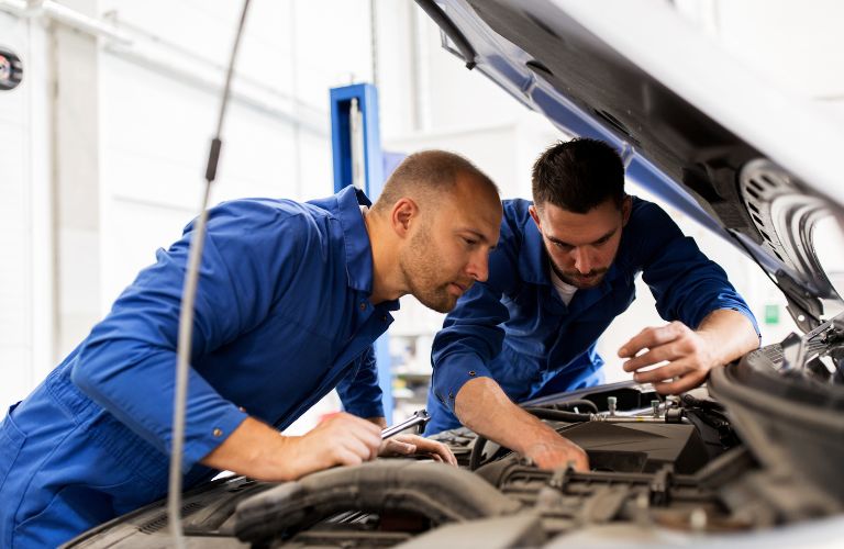 Car mechanics inspecting the engine of a vehicle